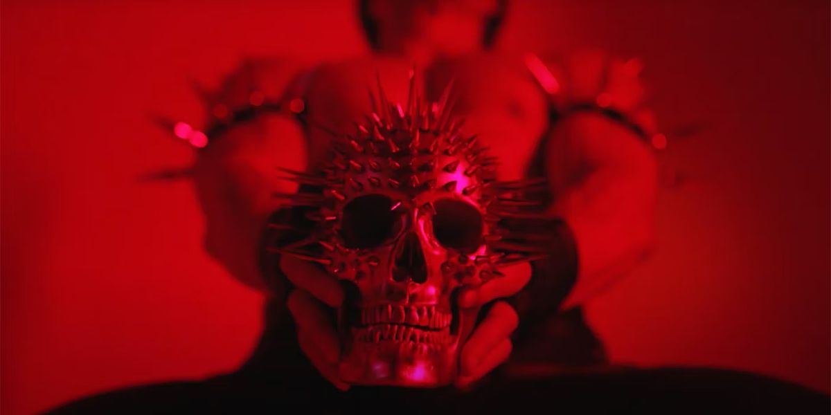 A red-tinged skull is held by a muscular person from American Horror Story.