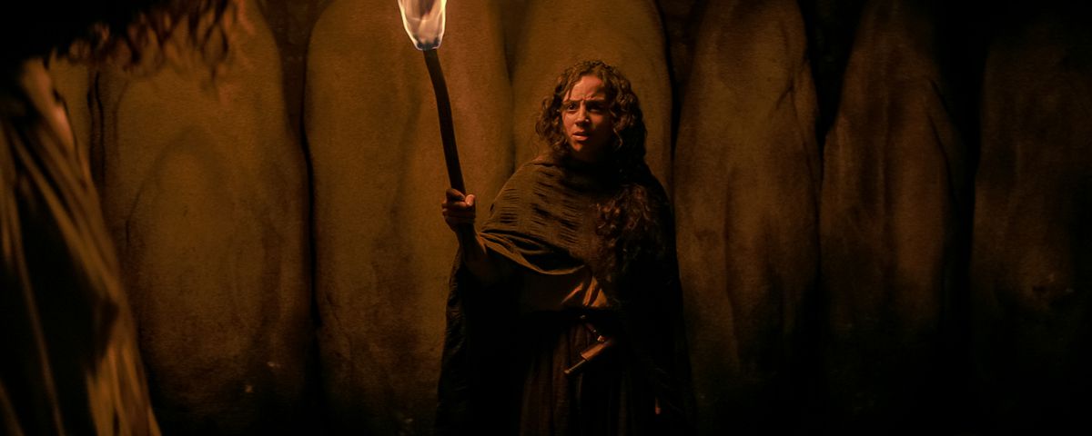 Kiana Madeira as Sarah Fier holding a torch and starring offscreen in Fear Street Part Three: 1666