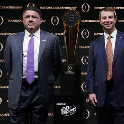 LSU head coach Ed Orgeron, left, and Clemson head coach Dabo Swinney pose with the trophy after a news conference for the NCAA College Football Playoff national championship game Sunday, Jan. 12, 2020, in New Orleans.