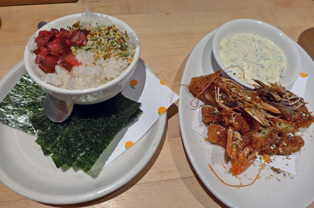 Two plates with rice, pickles, and nori on one and shrimp and tartar sauce on the other.
