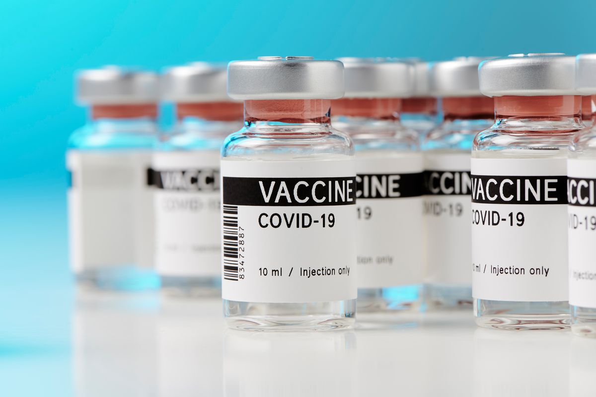 Several vials labeled VACCINE COVID-19 lined up against a light blue background