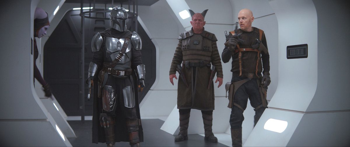 the mandalorian, a devil man, and bill burr stand on a prison ship