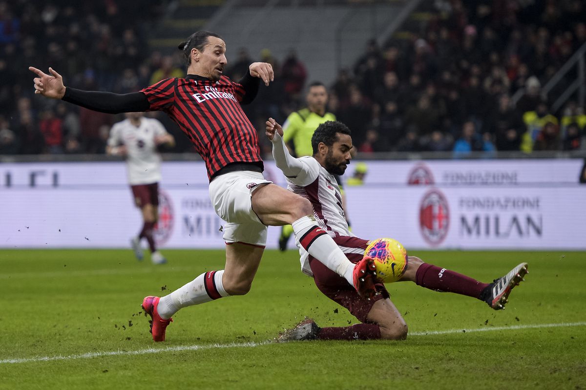 Zlatan Ibrahimovic (L) of AC Milan is tackled by Koffi...