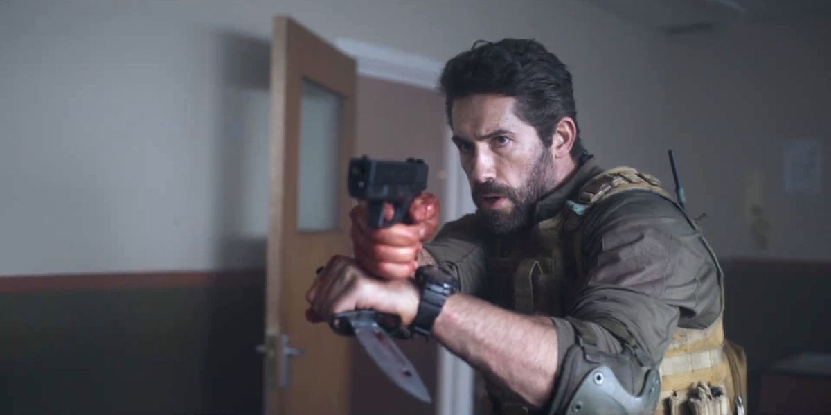 Scott Adkins as Jake Harris with a gun and knife in One Shot.