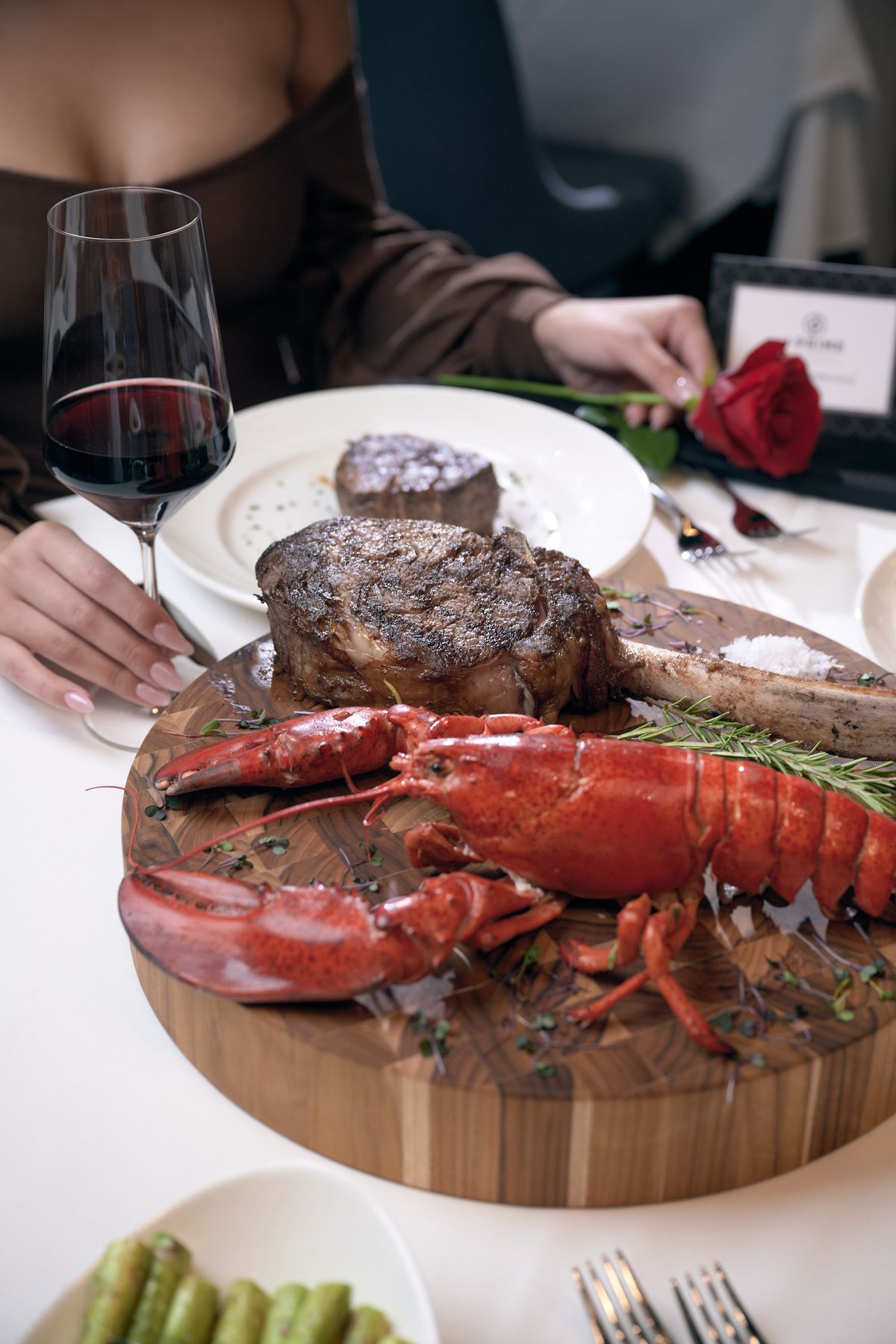 A round wooden plate of steak and lobster.