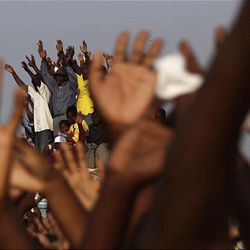 People raise their hands as they gather for the national day of mourning outside the national palace in Port-au-Prince, Friday.