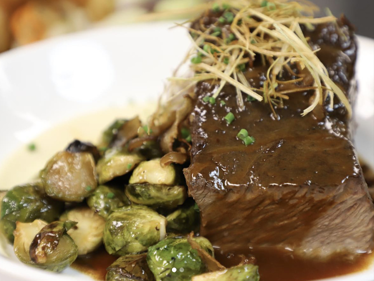 Braised short rib with honey glazed Brussels sprouts on a plate.