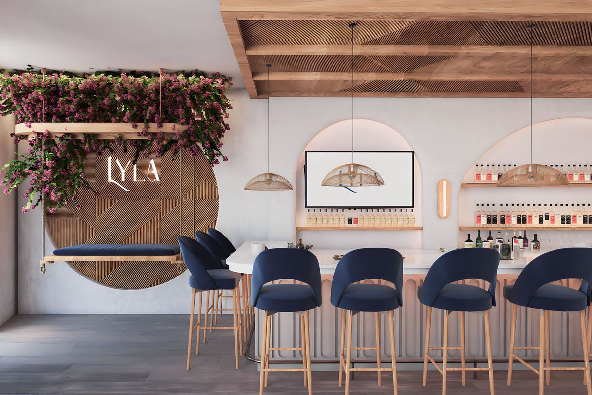 A bar space with tan walls and warm wood accents also features barstools with wooden legs and navy blue seats.