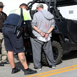 Salt Lake City police officer James Bishop returns belongings to the pants pocket of a man in handcuffs during Operation Rio Grande in Salt Lake City on Tuesday, Aug. 15, 2017.