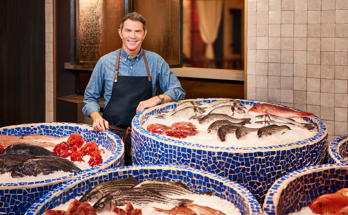 A man stands in front of circular bins of ice filled with seafood