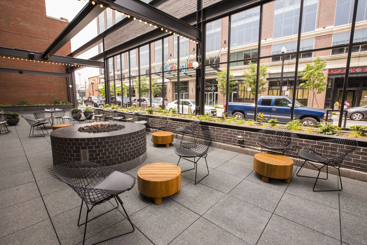 A modern outdoor patio with metal furniture and a round fire pit.