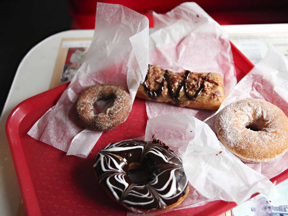 Four donuts on paper on a red tray. 