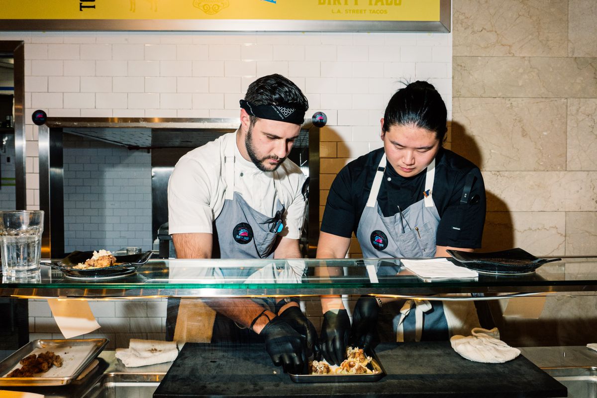 The chefs Jake Geragos, left, and Tae Woo Lee stand behind the counter of their restaurant, Dirty Taco.