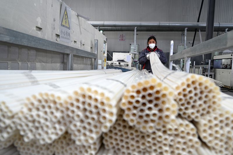A worker holding a bundle of long PVC pipes.