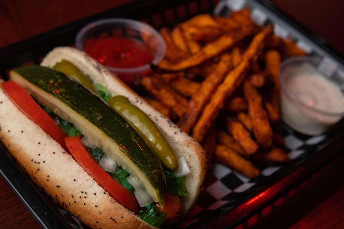 A pickle-topped Chicago-style hot dog and sweet potato fries at Tiny’s Hi-Dive.