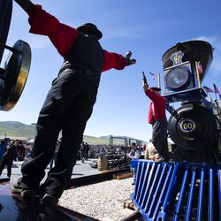 Tom Brown, locomotive engineer, and Patrick Jeffery, Park Service engine crew volunteer, stretch their arms out from the Union Pacific No. 119, left, and the Jupiter, Central Pacific’s No. 60, as they depict the champaign toast during the Golden Spike Sesquicentennial Celebration and Festival at Promontory Summit on Friday, May 10, 2019.