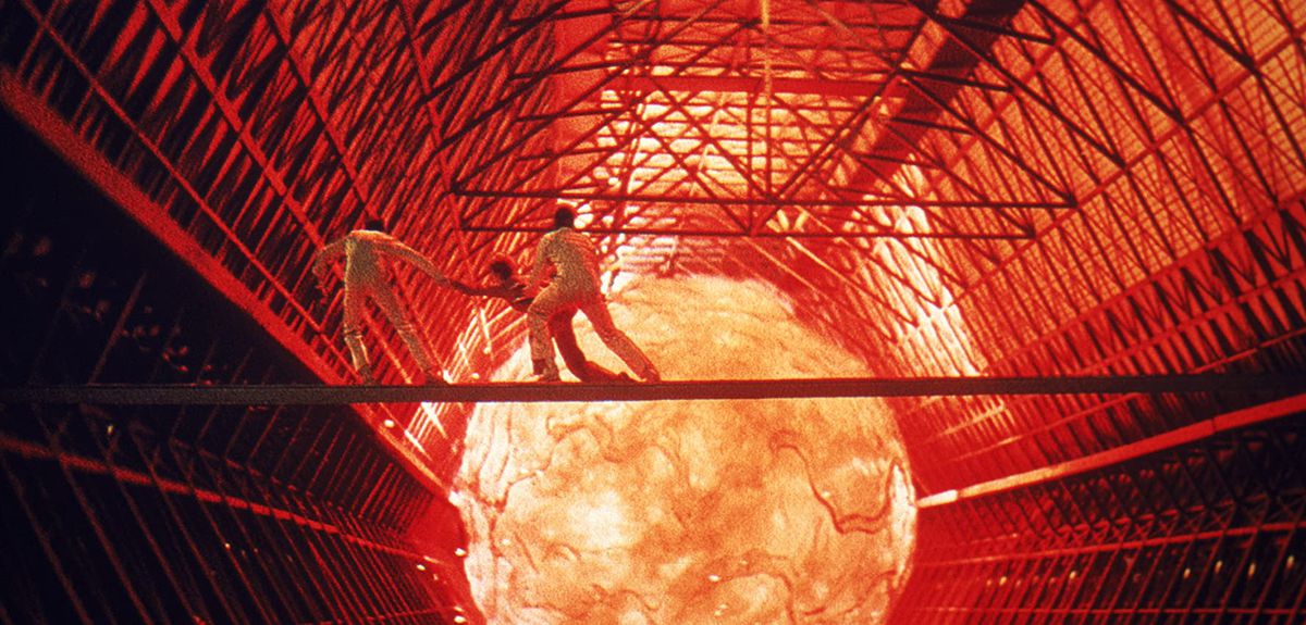 Workers run away from a molten orb in a screenshot from The Black Hole