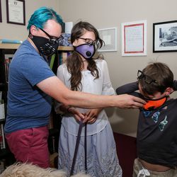 Rob Weidmann, left, and Sophie Weidmann, 13, help Max Weidmann, 10, put on his air pollution masks at their home in Salt Lake City on Thursday, Nov. 8, 2018.