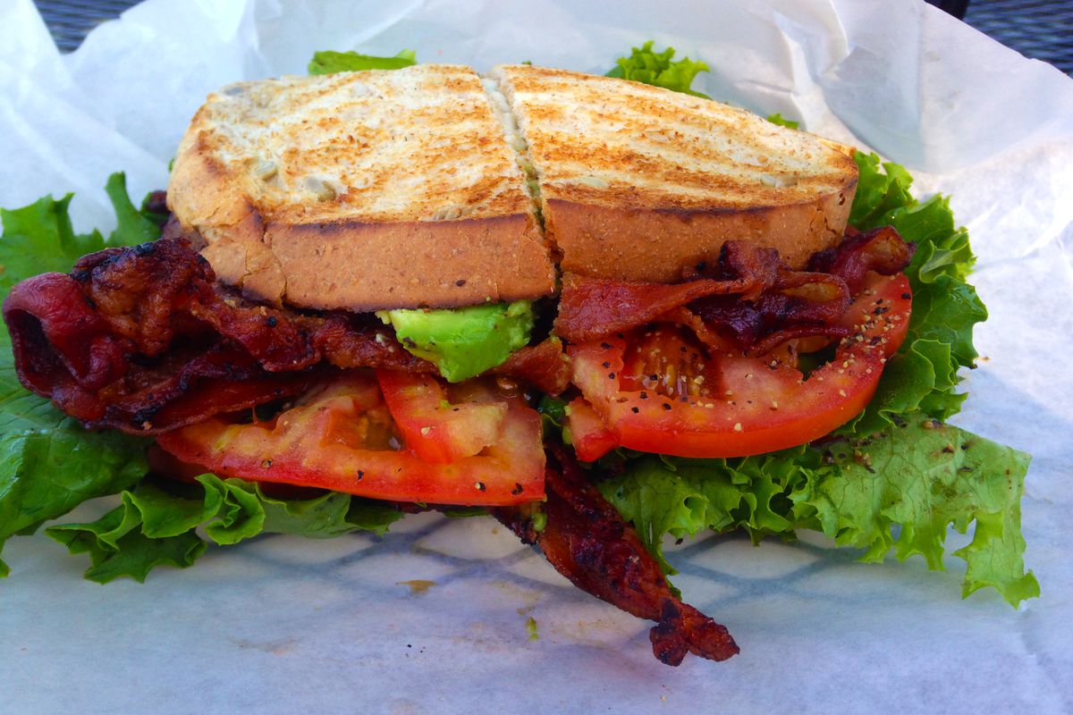 A very thick BLT sandwich on white paper. 
