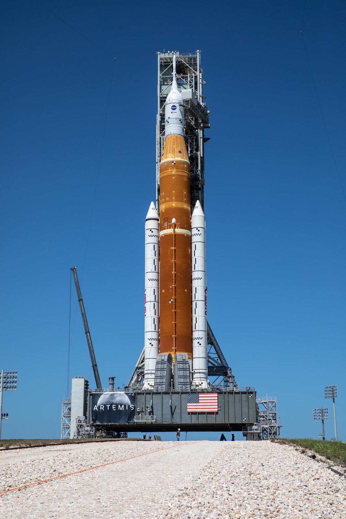 El cohete SLS en una gran plataforma con un camino rocoso en primer plano.