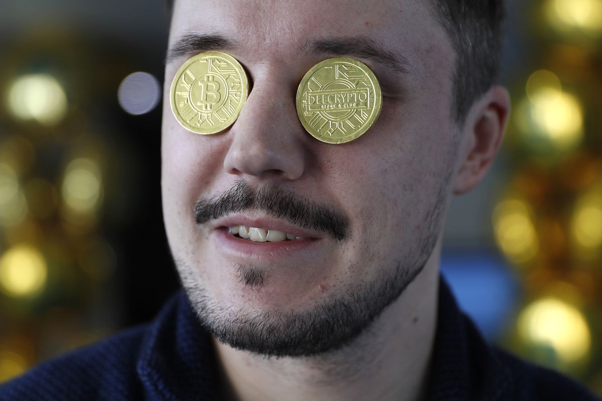 A man’s face with gold coins representing bitcoins over his eyes.