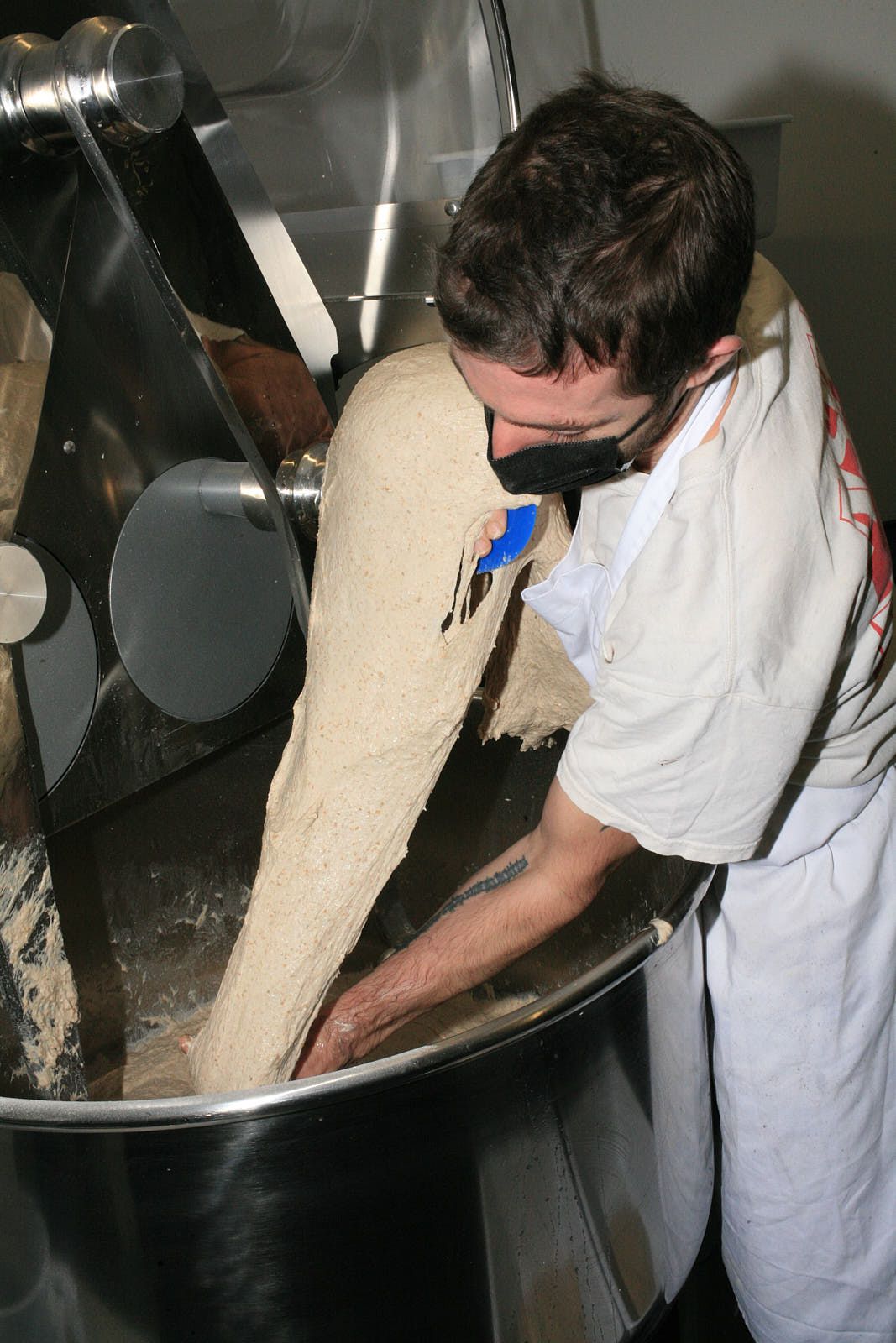 A baker pulls dough from a standmixer