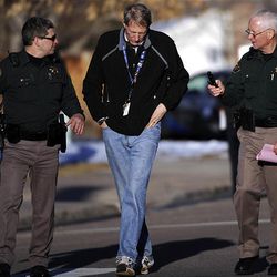 Dr. David Benke is escorted by Jefferson County police officers to a patrol car in front of Deer Creek Middle School after a shooting in Littleton, Colo., Tuesday