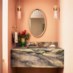 Interior designer Meghan Shadrick included some special touches to spice up the powder room. A bold stone vanity was crafted from leftover pieces of the Blue Explosion quartzite slab that tops the kitchen island. A Moroccan-inspired wallpaper covers the ceiling.