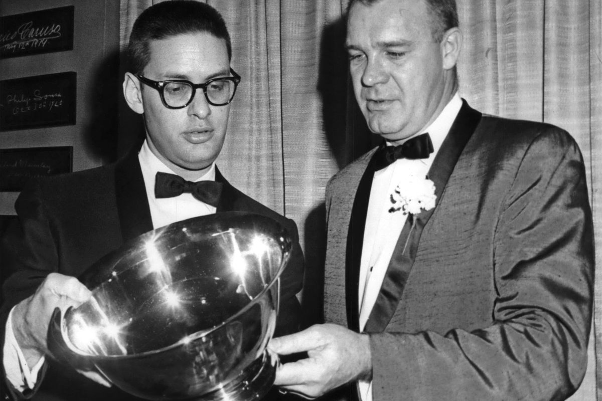 A much much younger Bud Selig and another gentleman examine a trophy The picture is black and white, and both men are wearing suits. The other gentleman has a flower in his lapel