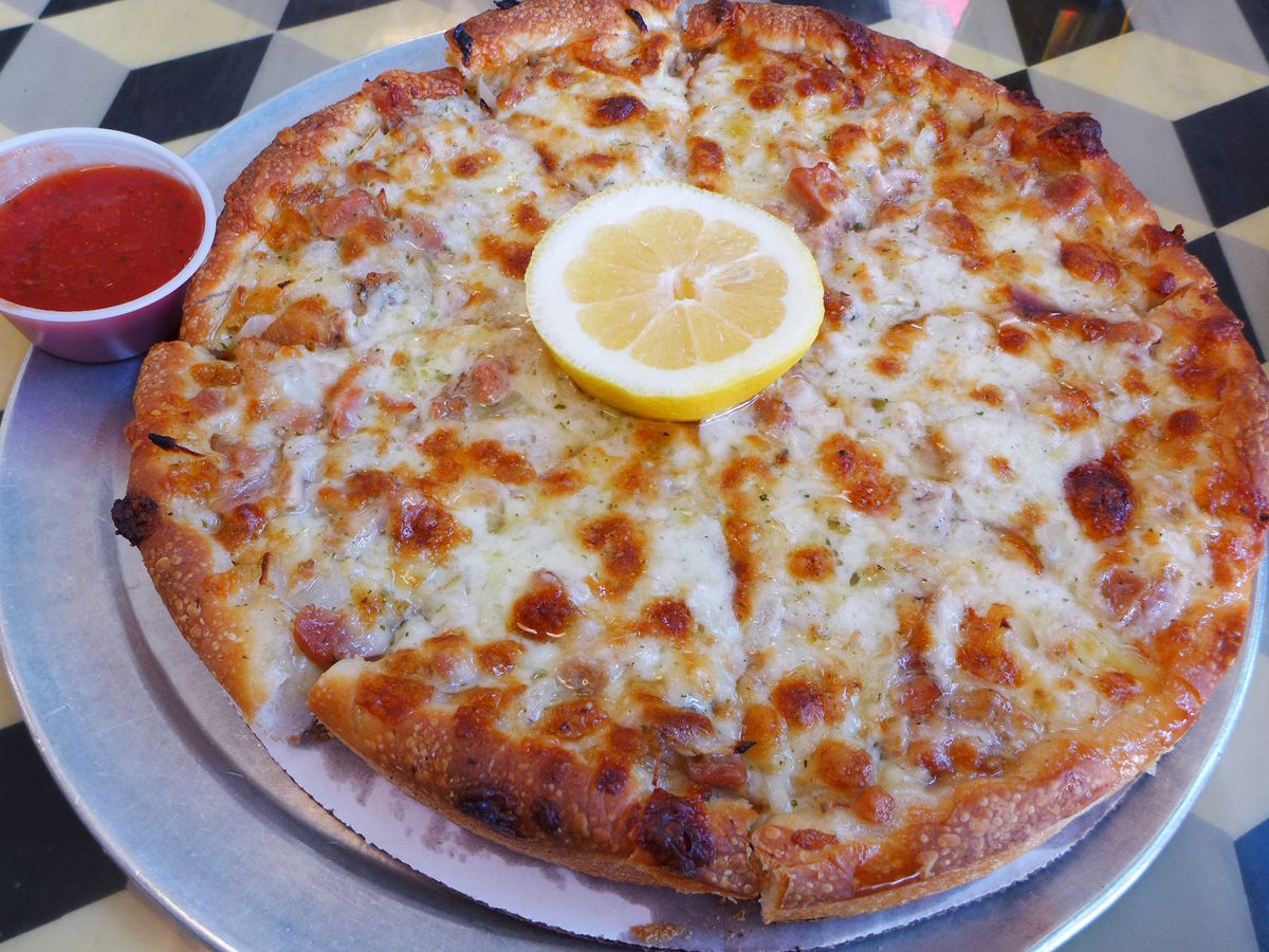 A round clam pizza with a lemon slice in the middle.