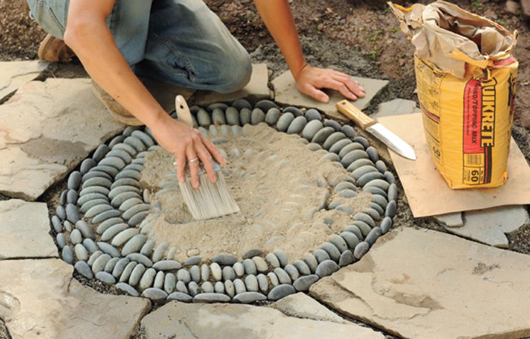 Person Spreads Topping Mix Over Pebble Mosaic