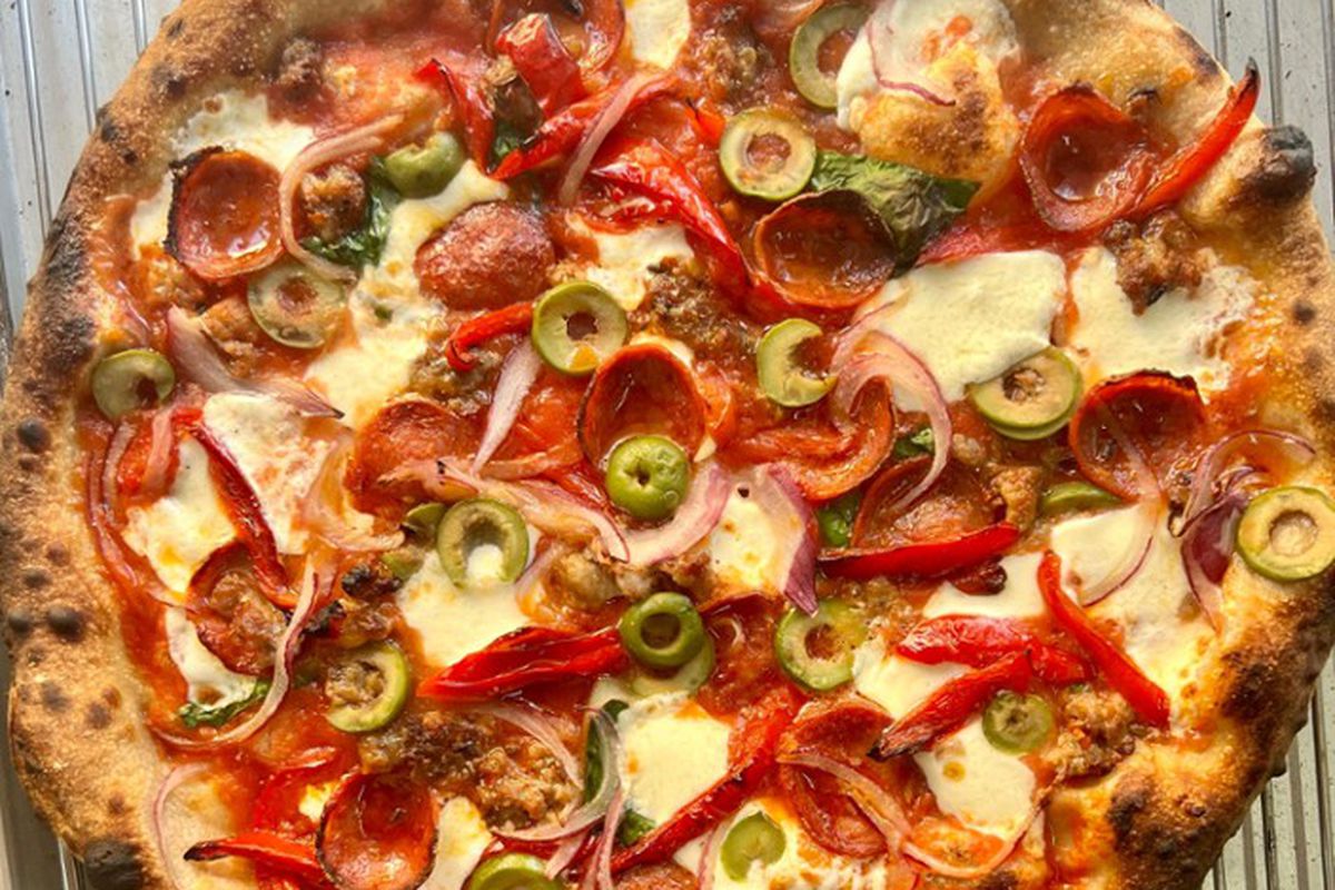 A pizza with meats and vegetables.