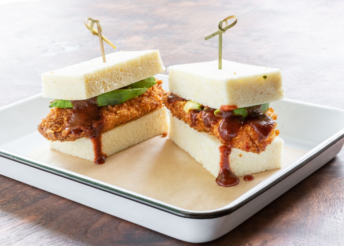 A sandwich of fried chicken on white milk bread, dripping with chamoy sauce