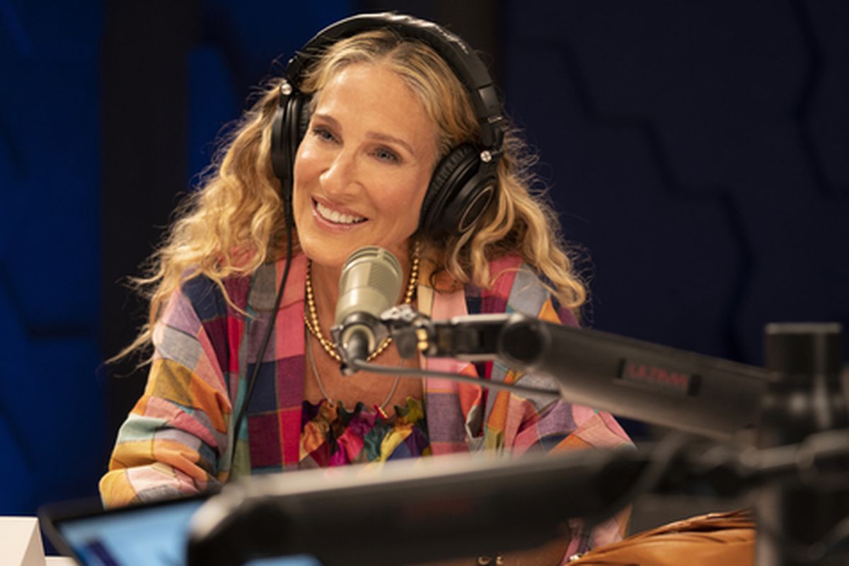 Sarah Jessica Parker as Carrie Bradshaw wearing headphones and sitting at a recording microphone.