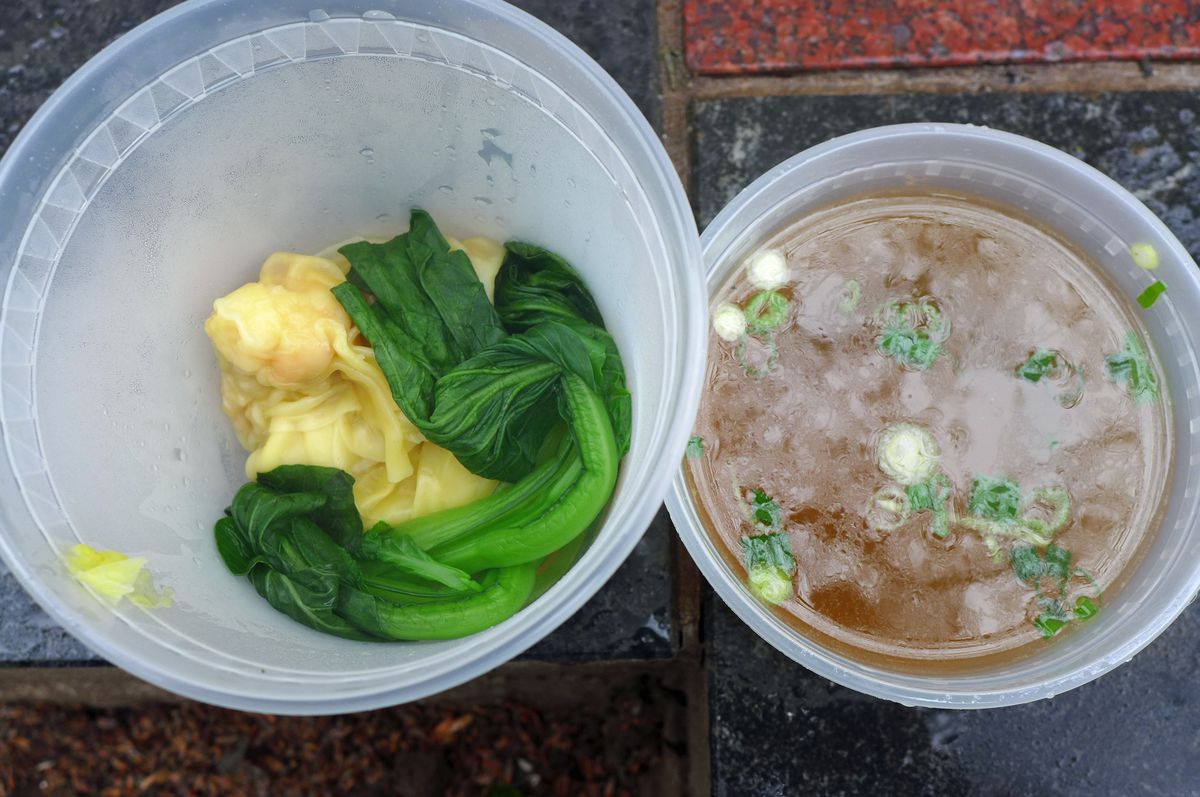 Two containers, one with dumplings and greens, the other with broth.