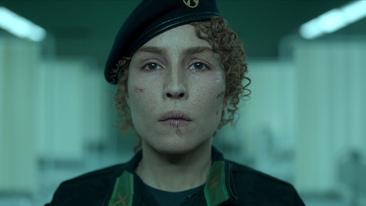 A battered-looking Noomi Rapace, in military beret, looks into the camera in the Swedish action thriller Black Crab