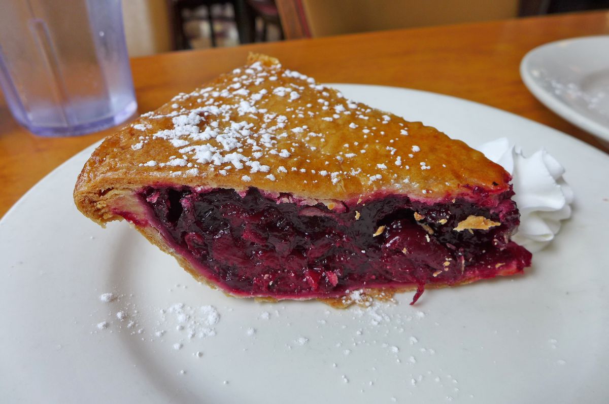 A wedge of cherry pie on a white plate.