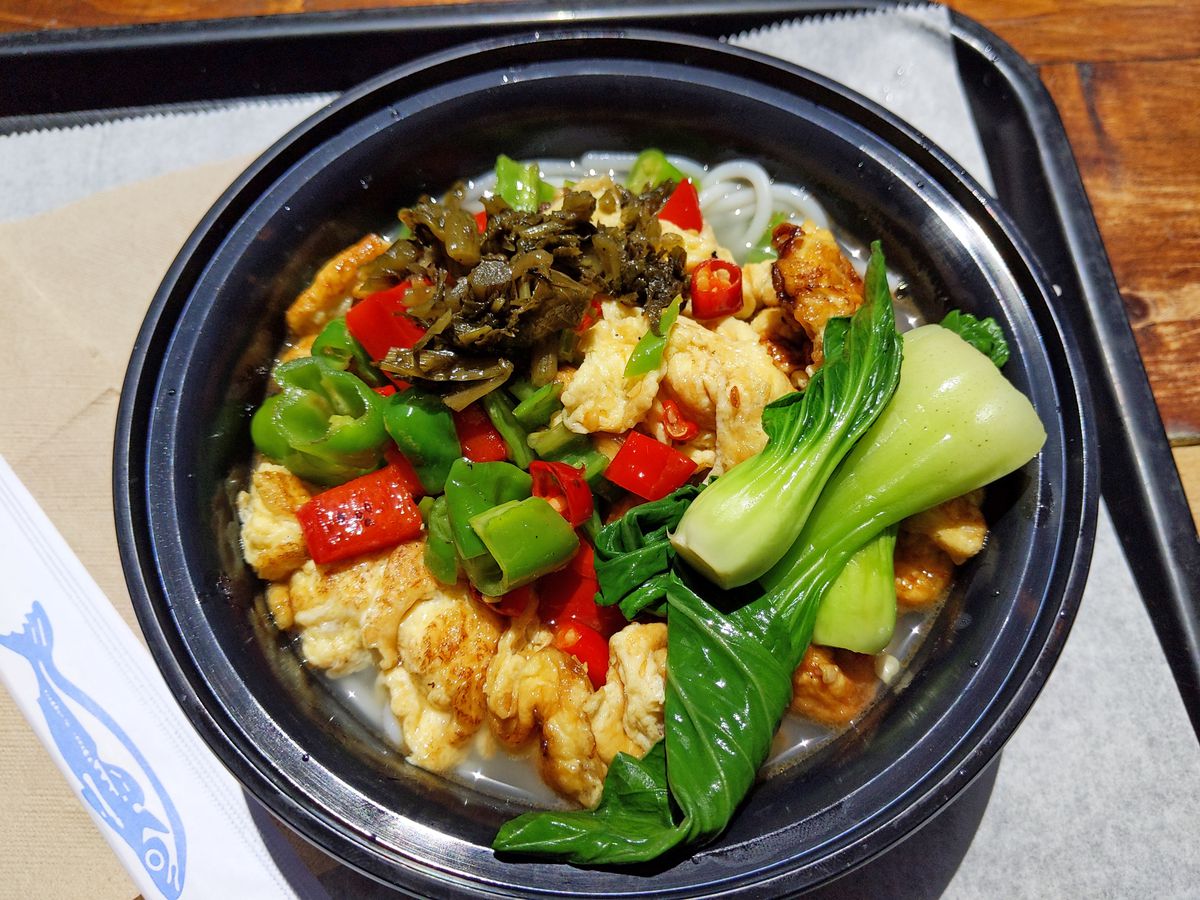 A round black plastic bowl with eggs and green peppers.