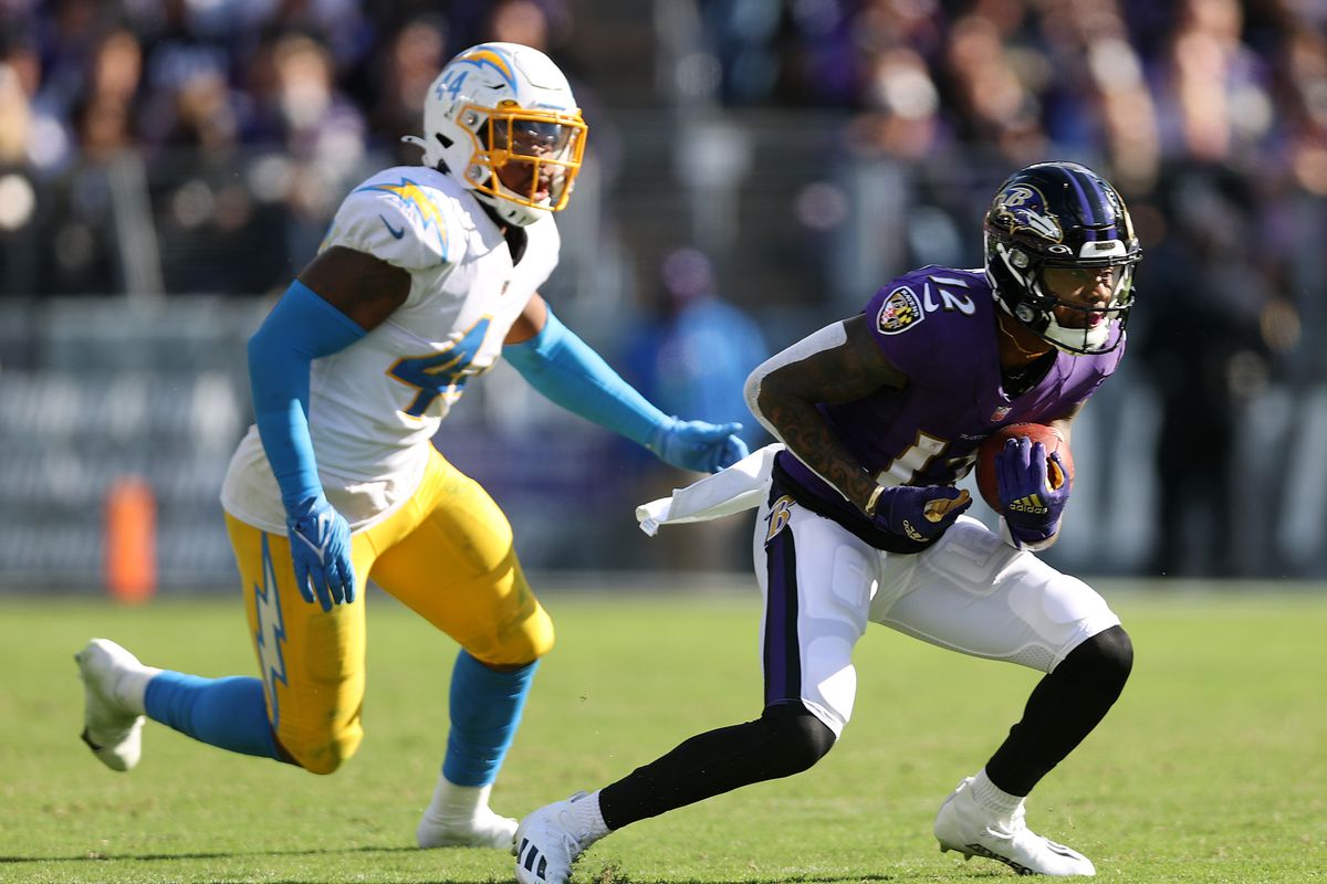 Rashod Bateman #12 of the Baltimore Ravens runs with the ball against Kyzir White #44 of the Los Angeles Chargers during the third quarter at M&amp;T Bank Stadium on October 17, 2021 in Baltimore, Maryland.