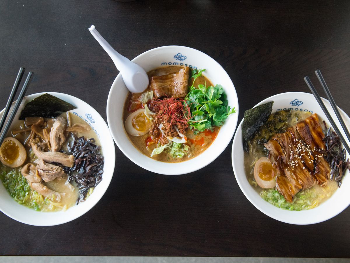 A bird’s eye view of three bowls of ramen soup, with chopsticks and a spoon laying on top. From left to right: Tokyo chicken soup, spicy tan-tan, and tonkatsu ramen.