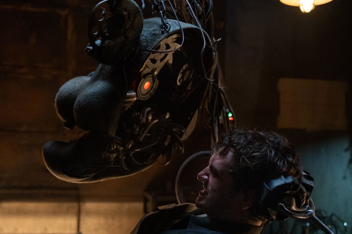Hapless night security guard Mike (Josh Hutcherson) winces as the inside of an animatronic bear’s faceplace, complete with glowing red eye and threatening fan blade, approaches his head in the Five Nights at Freddy’s movie