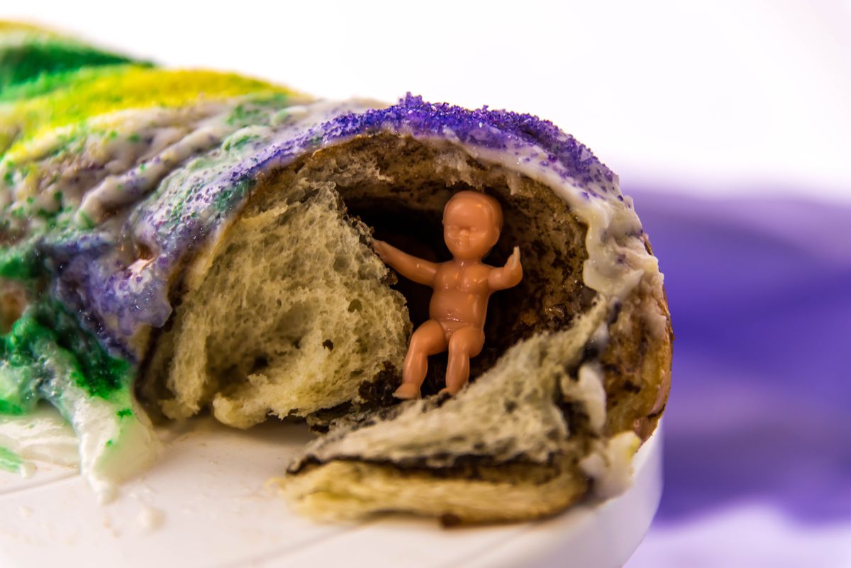 Plastic baby figurine inside a cross-section of king cake.