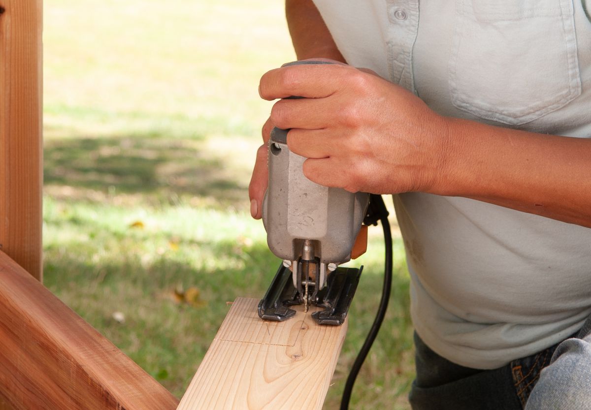Man Cuts Seat Boards Of Arbor Bench