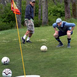 In this April 26, 2014 photo, Meadow Park Golf Course superintendent Chris Goodman, right, watches his shot miss to the amusement of Dennis Roque during a round of Footgolf at Meadow Park Golf Course, in Tocoma, Wash. In addition to the 21-inch-wide holes, there are a few other changes to the golf game. The holes are shorter and one can play 18 holes in about 90 minutes. 