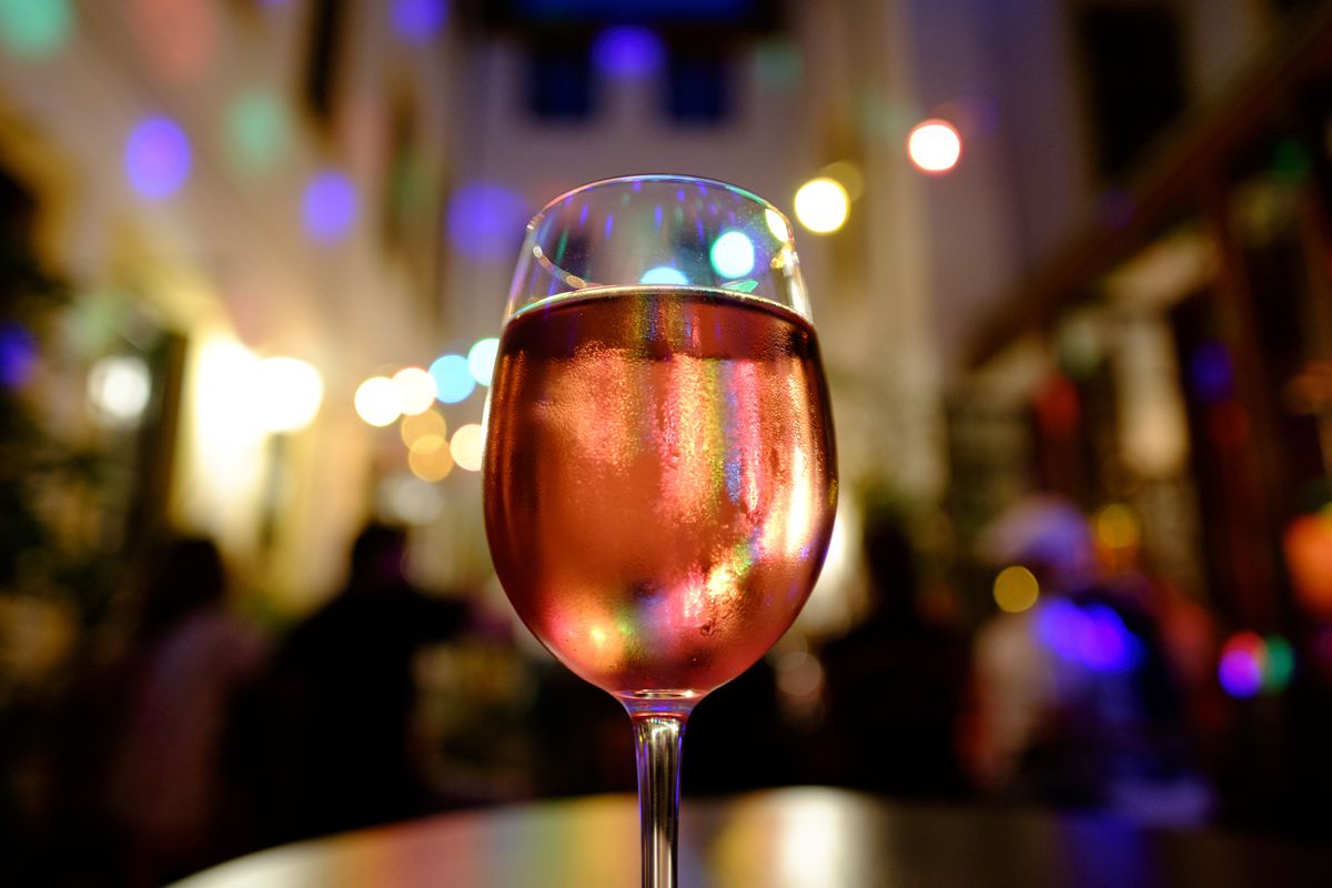 A close up on a large glass of pink wine with a twinkly night time backdrop 