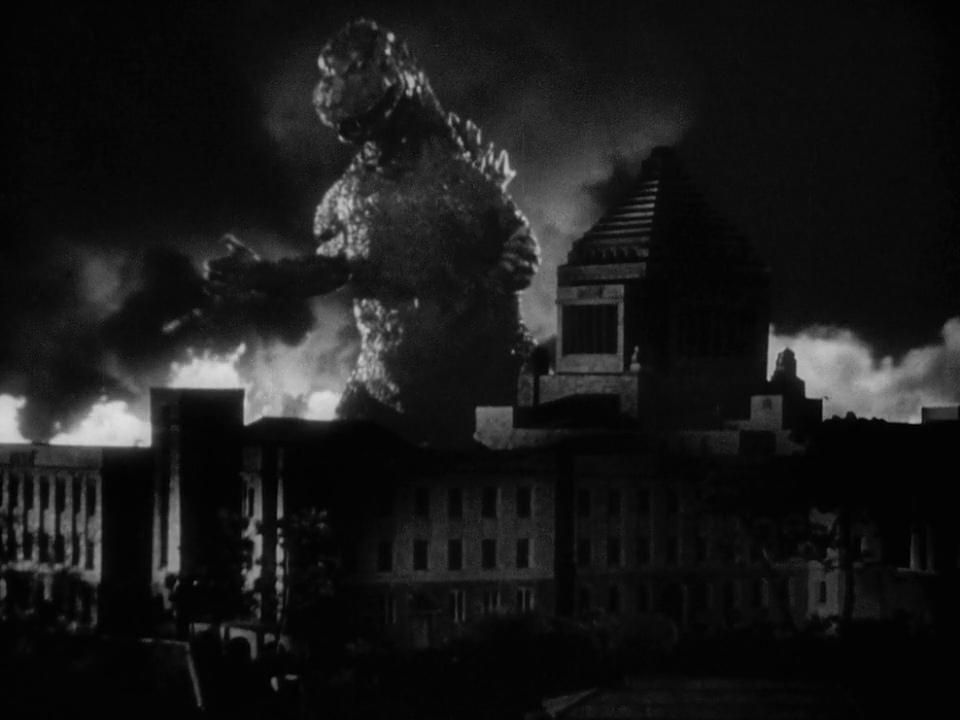 Godzilla looming over a building in a shot from the original Godzilla movie