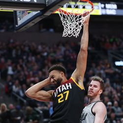 Utah Jazz center Rudy Gobert (27) holds his head after dunking and being fouled as San Antonio Spurs center Jakob Poeltl (25) defends at Vivint Arena in Salt Lake City on Friday, Dec. 17, 2021.