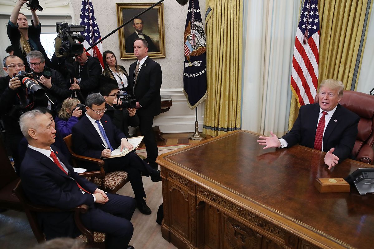 President Trump siting behind a desk in the Oval Office with press and Chinese Vice Premier Liu He sitting in attendance.