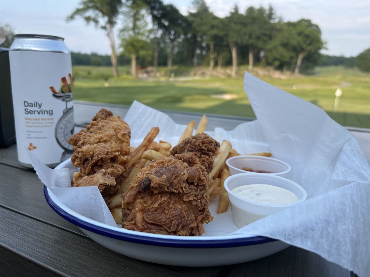 A plate of fried chicken, fries, and ranch and ketchup with a Trillium beer can visible in the background.