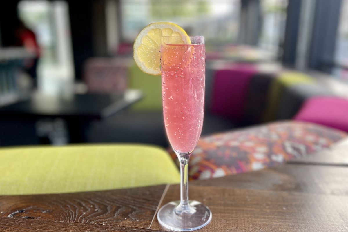 Fizzy “Pretty in Pink” cocktail in a champagne glass with lemon slice as a garnish.